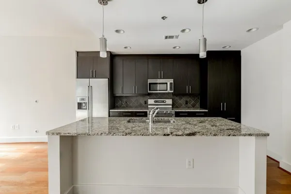 a kitchen with stainless steel appliances granite countertop a sink a stove and a refrigerator