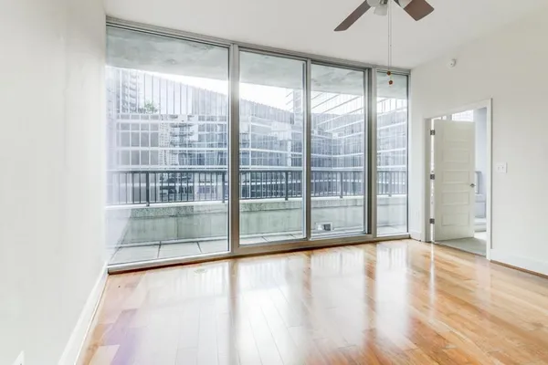 a view of an empty room with wooden floor and a window