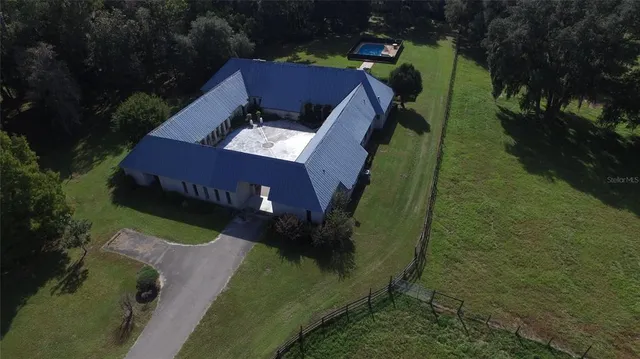 an aerial view of residential houses with outdoor space and trees