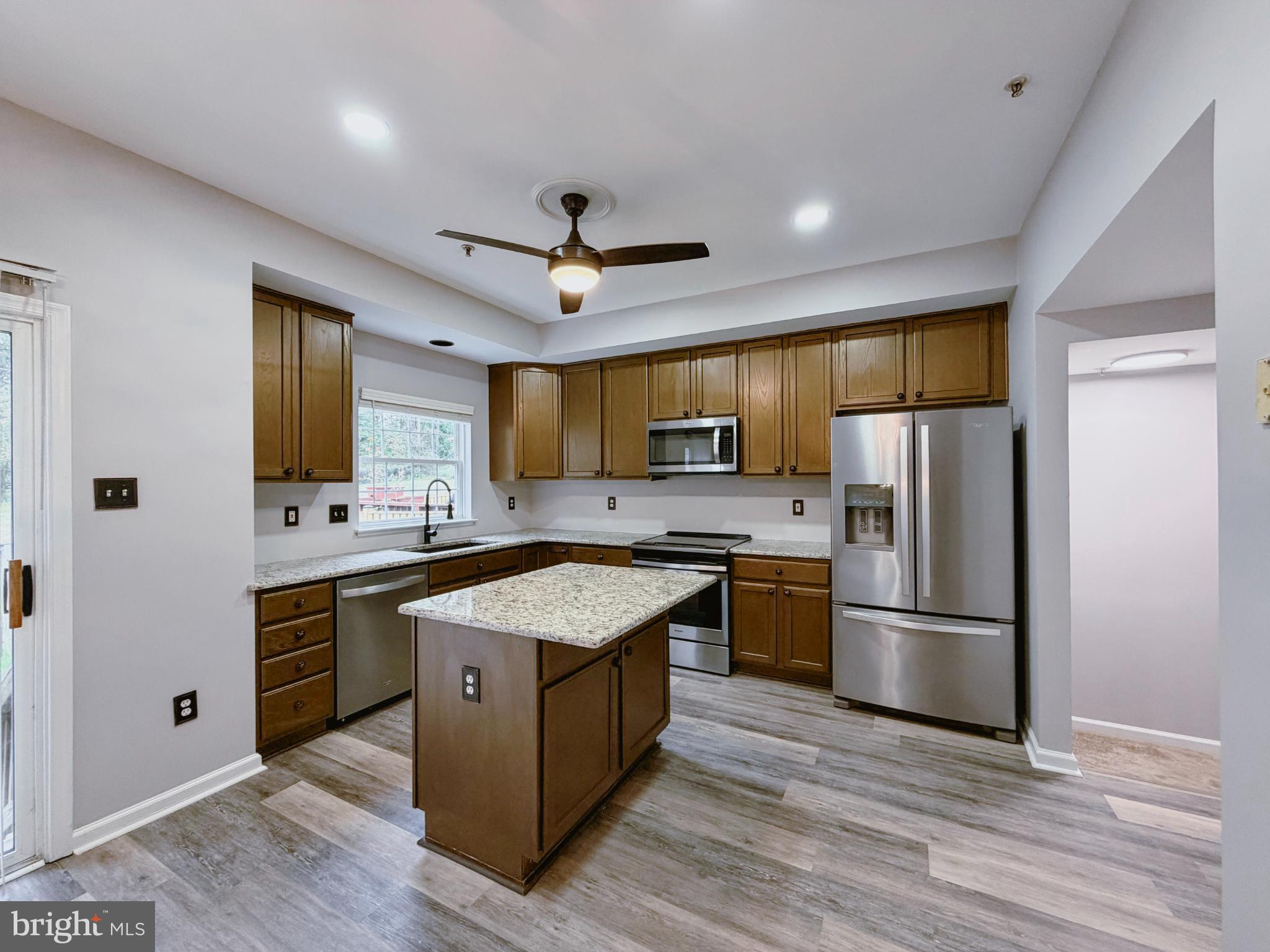 9837 Sherwood Farm Road Owings Mills, MD 21117 - Photo 6 of 27 a kitchen with a refrigerator a sink and dishwasher with wooden floor