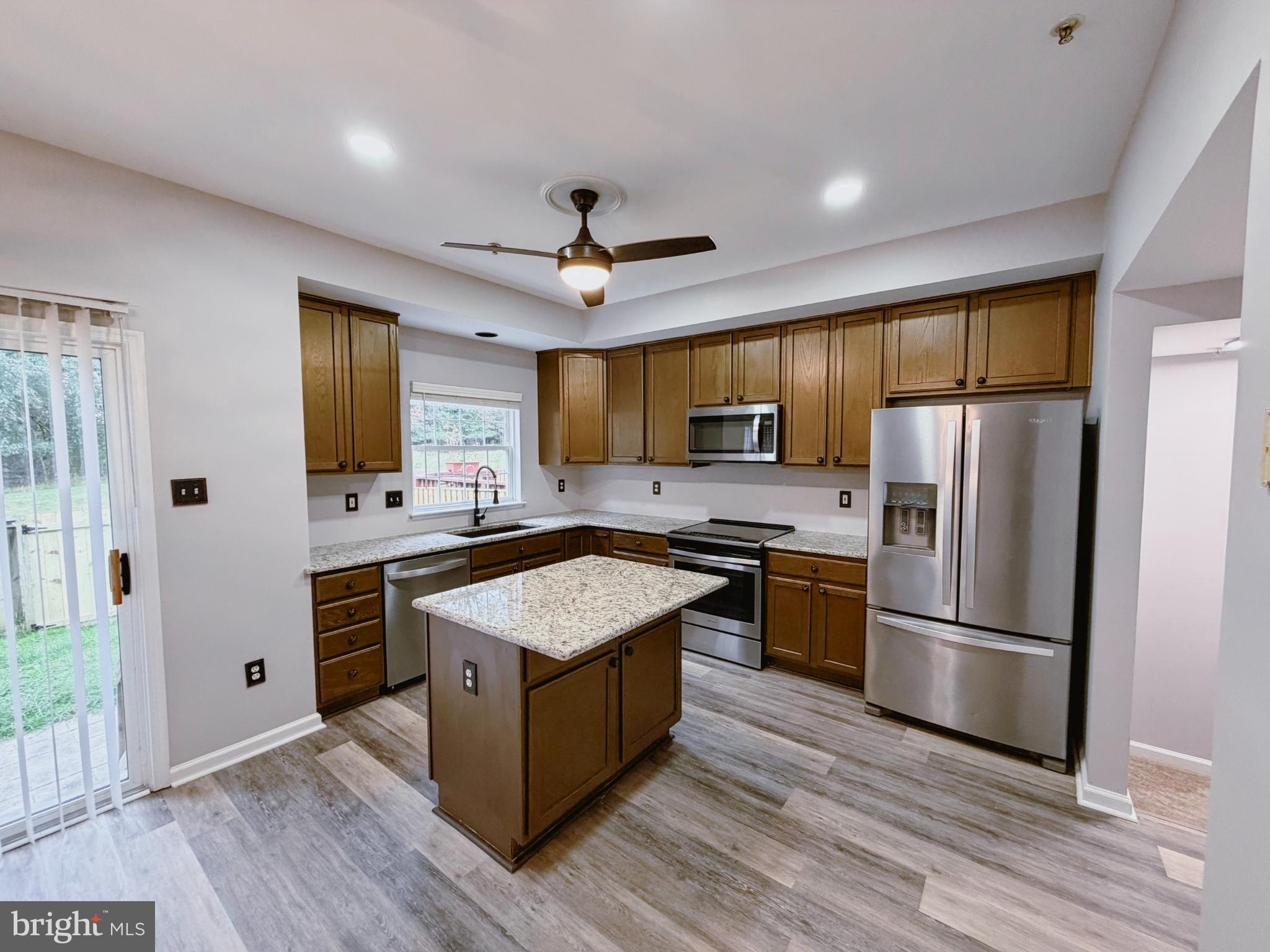 9837 Sherwood Farm Road Owings Mills, MD 21117 - Photo 7 of 27 a kitchen with stainless steel appliances granite countertop a refrigerator a stove top oven a sink dishwasher and wooden cabinets with wooden floor