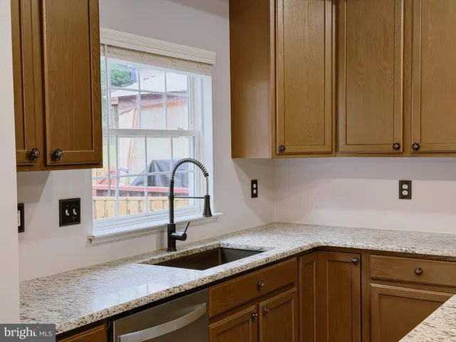 a kitchen with granite countertop a sink and a wooden cabinets
