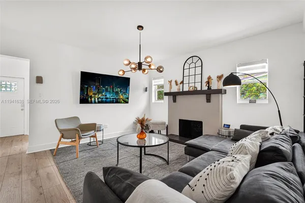 a living room with furniture kitchen view and a chandelier