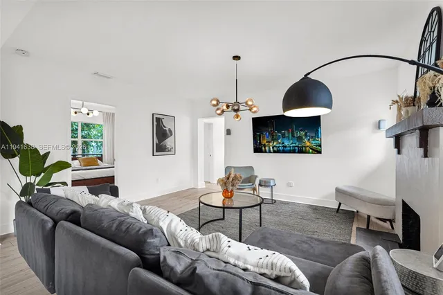 a living room with furniture kitchen view and a chandelier