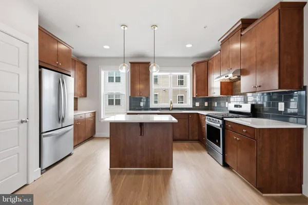 a kitchen with stainless steel appliances granite countertop a refrigerator a sink dishwasher a stove and a refrigerator