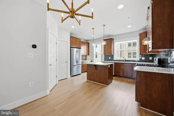 a large kitchen with stainless steel appliances kitchen island granite countertop a large counter top a sink and a refrigerator