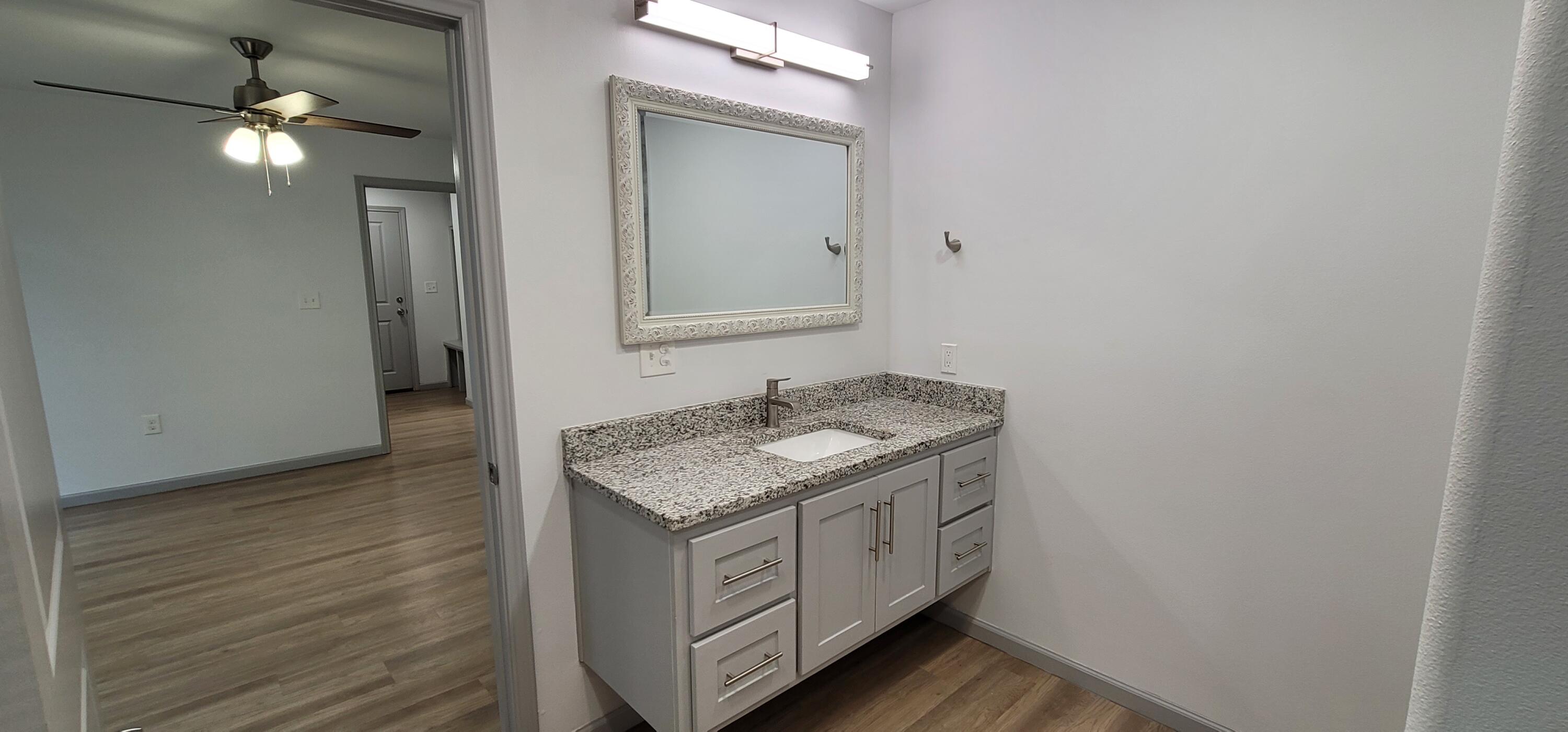 2110 88th Street Lubbock, TX 79423 - Photo 13 of 22 a bathroom with a granite countertop sink and a mirror