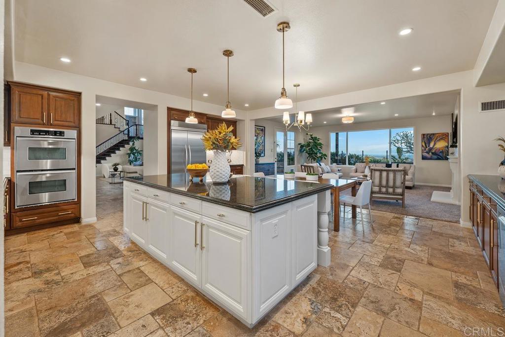 7603 Circulo Sequoia Carlsbad, CA 92009 - Photo 12 of 61 a kitchen with stainless steel appliances kitchen island granite countertop a table and chairs