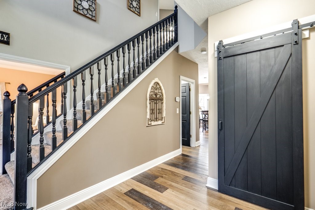 4121 New Milford Road Rootstown, OH 44272 - Photo 9 of 50 Staircase with a barn door, a towering ceiling, baseboards, and wood finished floors
