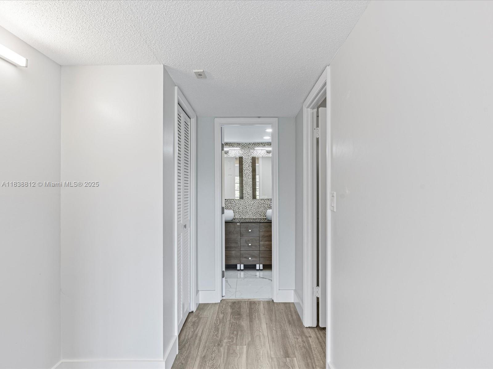 Palm Aire Pompano Beach, FL 33069 - Photo 17 of 26 a hallway with wooden floor and a bathroom