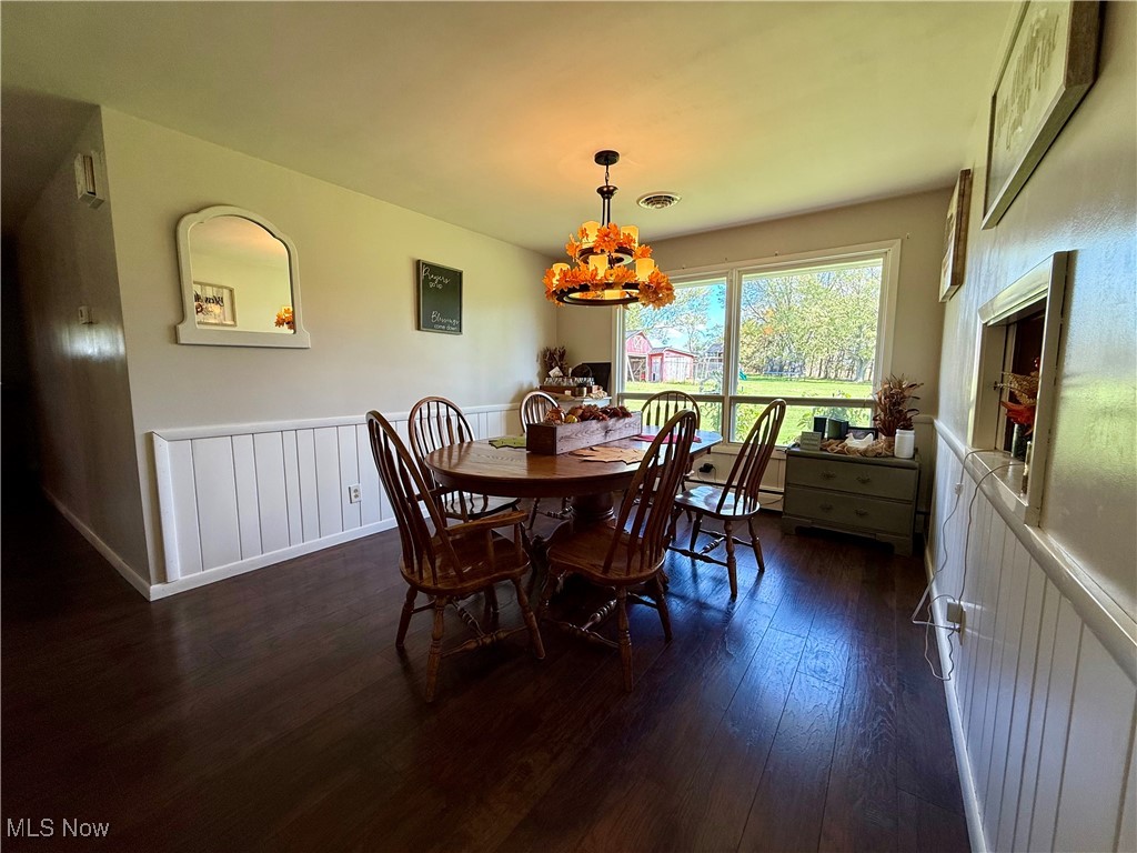 248 Scio Road Carrollton, OH 44615 - Photo 7 of 33 Dining room featuring a wainscoted wall, dark wood-type flooring, and a chandelier