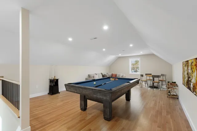 a room with furniture pool table wooden floor and windows