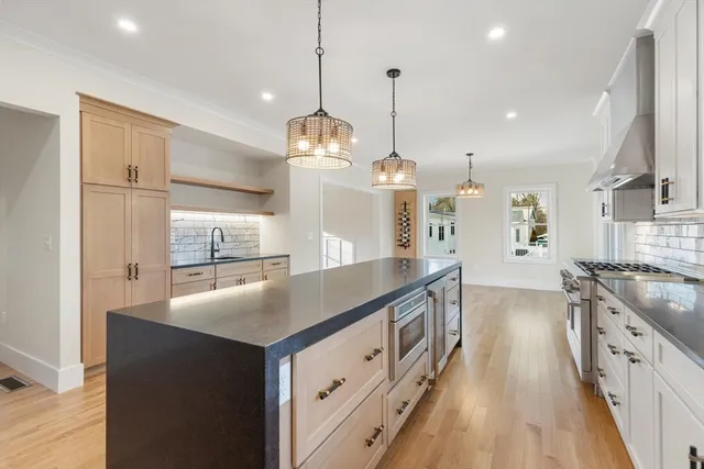a kitchen with stainless steel appliances granite countertop a sink a stove and a wooden floors