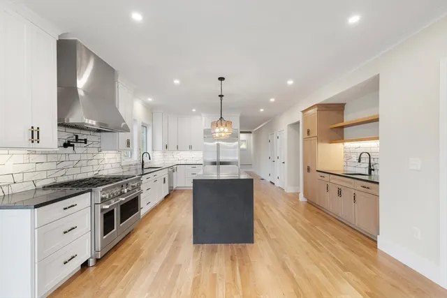 a large kitchen with stainless steel appliances kitchen island a large counter top and a wooden floors