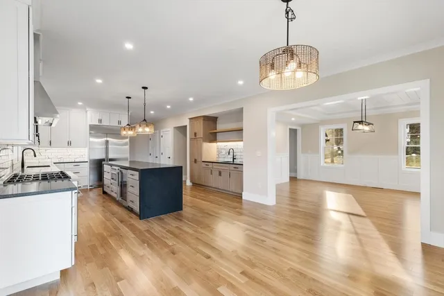 a large kitchen with stainless steel appliances kitchen island a large counter top and wooden floors