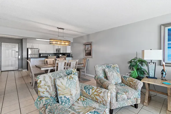 a dining room with stainless steel appliances kitchen island granite countertop a dining table chairs and a refrigerator