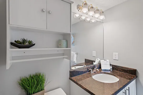 a bathroom with a granite countertop sink a toilet and shower