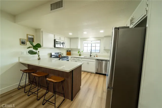 a kitchen with stainless steel appliances a sink a stove a refrigerator and cabinets
