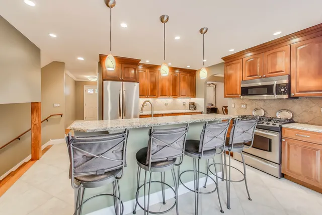 a kitchen with stainless steel appliances granite countertop a refrigerator a stove and white cabinets with wooden floor