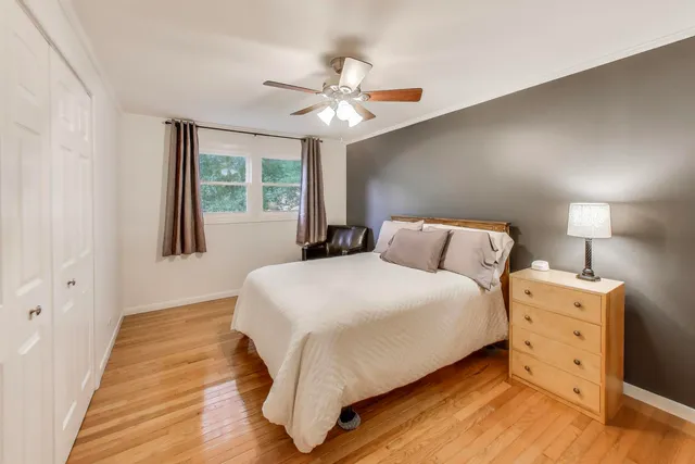 an empty room with wooden floor fan and windows