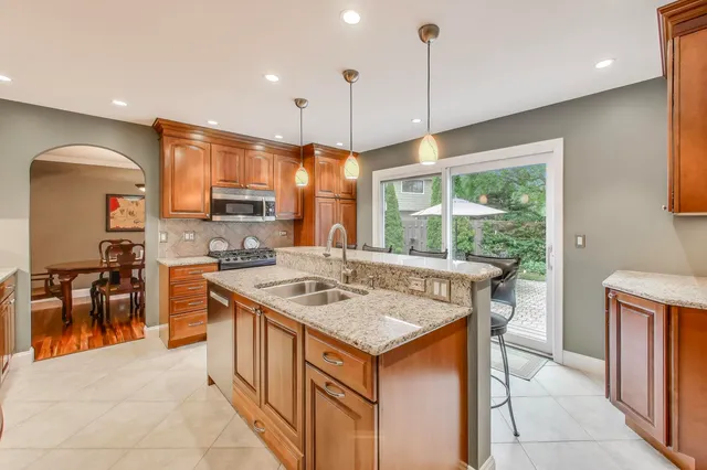 a kitchen with stainless steel appliances granite countertop a stove a refrigerator a oven a sink with a dining table and chairs