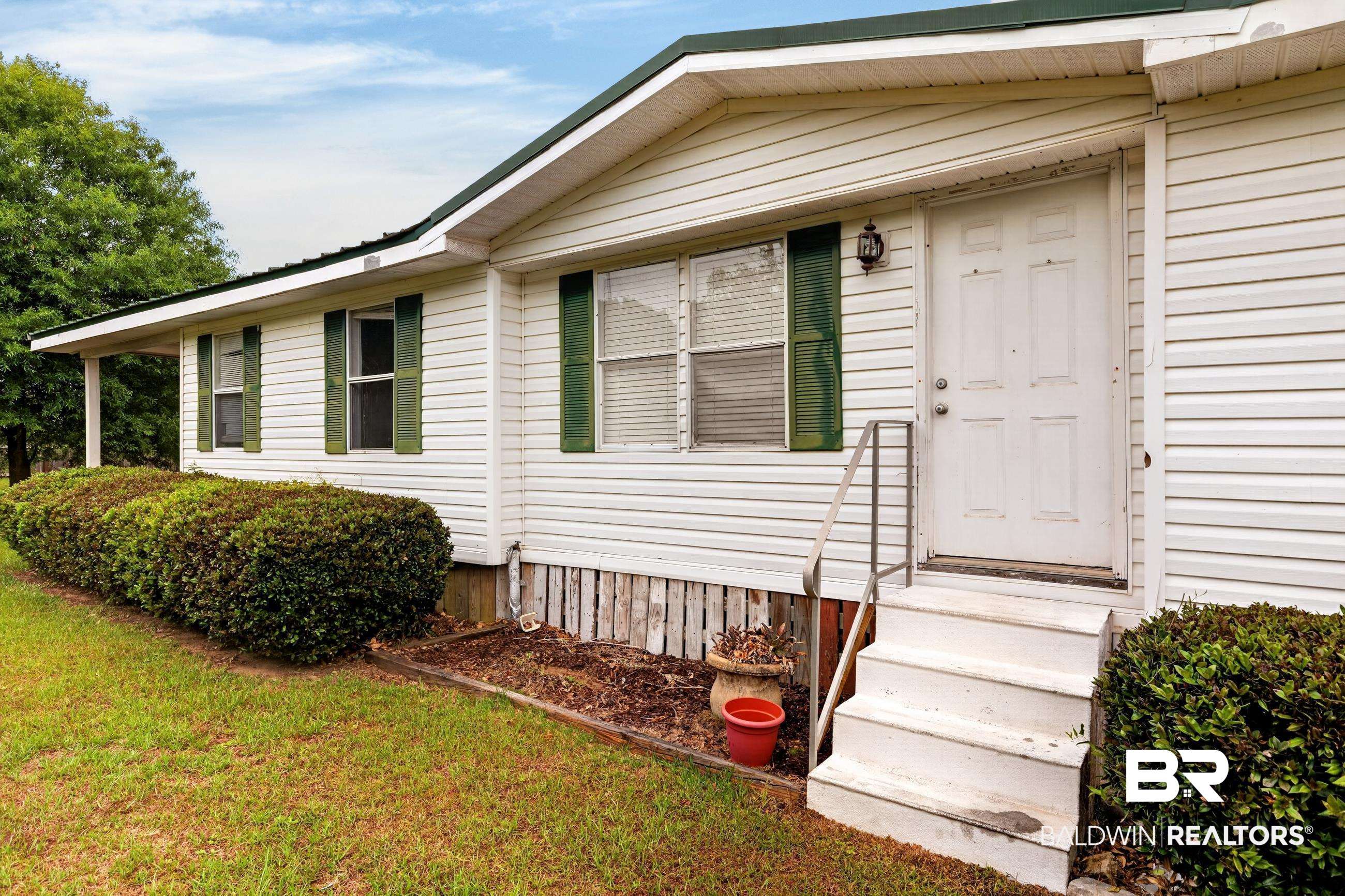 24903 Patterson Road Robertsdale, AL 36567 - Photo 22 of 57 White vinyl siding exterior with a green metal roof