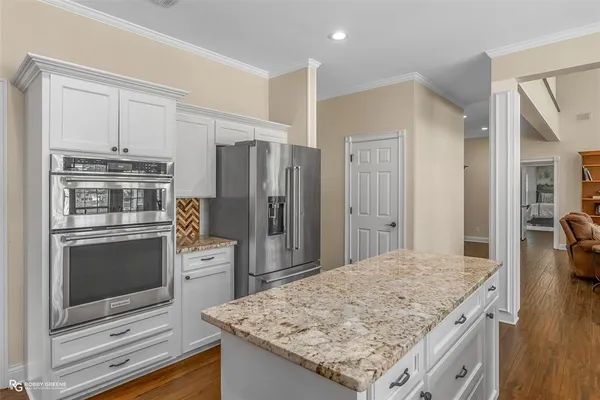 a kitchen with stainless steel appliances kitchen island granite countertop a refrigerator stove and oven