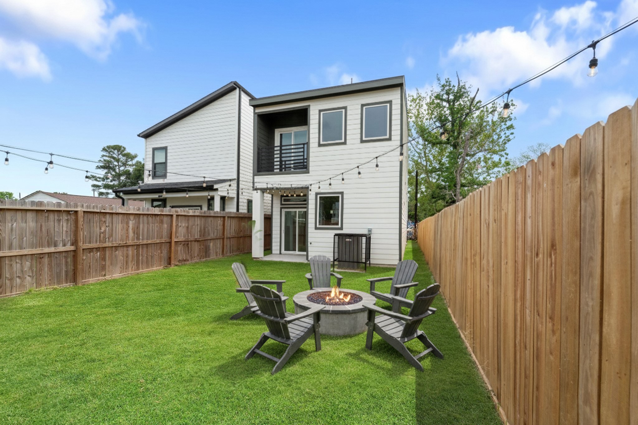 7709 Willow Street Houston, TX 77088 - Photo 2 of 15 The view shows the rear exterior of the home. The large grassy yard is enclosed by a tall wooden privacy fence.