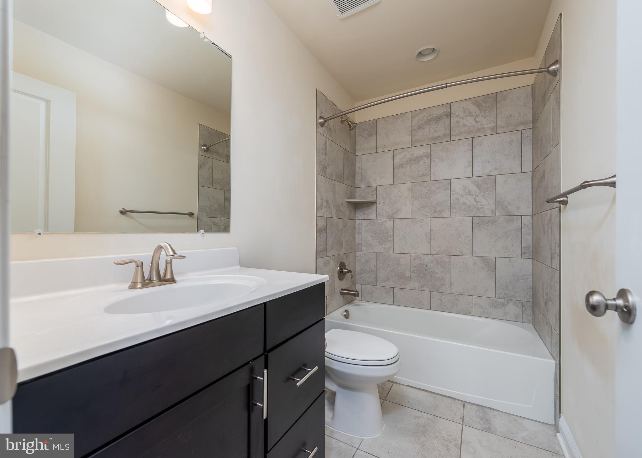 7038 Rackham Way Hanover, MD 21076 - Photo 16 of 30 a bathroom with a bathtub shower sink mirror and toilet
