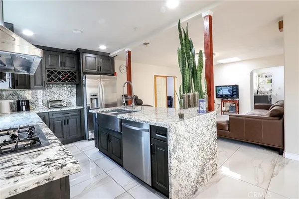 a kitchen with stainless steel appliances kitchen island granite countertop a stove refrigerator and cabinets