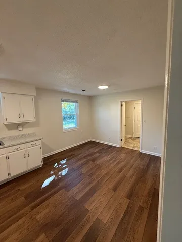 a view of an empty room with window and wooden floor