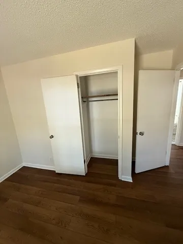 a view of an empty room with wooden floor and closet