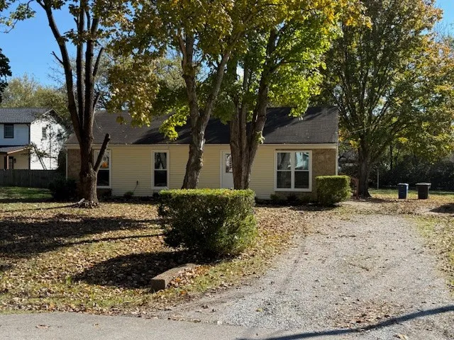 a front view of a house with a yard covered with trees