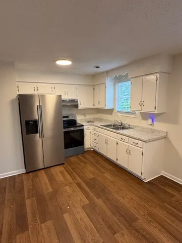 a kitchen with granite countertop a refrigerator stove top oven and sink