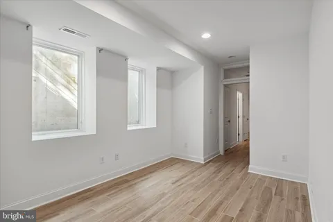 an empty room with wooden floor and windows