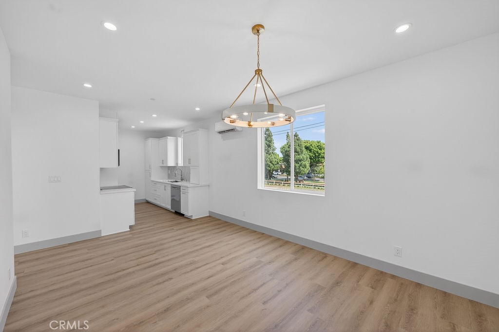 15540 Colorado Avenue Paramount, CA 90723 - Photo 58 of 63 an empty room with wooden floor kitchen view and a chandelier