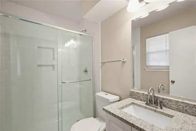 a bathroom with a granite countertop sink toilet and shower