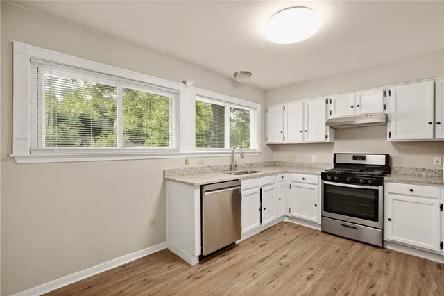 a kitchen with a stove a sink and wooden floor