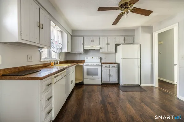 a kitchen with a white cabinets a sink a refrigerator and wooden floor