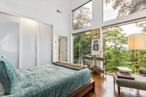 a bedroom with a bed and large windows