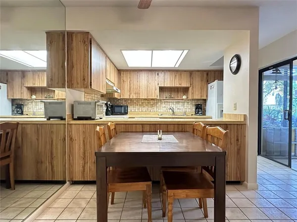 a kitchen with stainless steel appliances kitchen island granite countertop a table chairs and a refrigerator