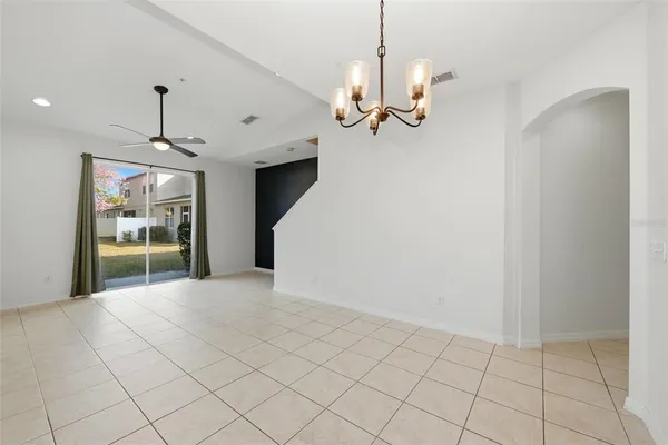 a view of a livingroom with a chandelier windows and kitchen view