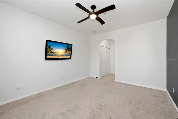 an empty room with windows and ceiling fan