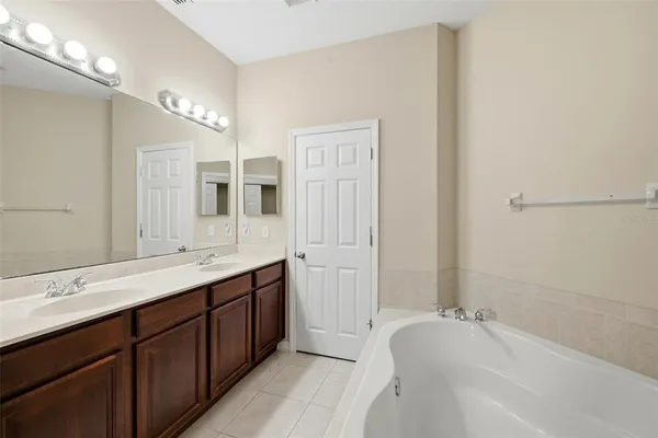 a spacious bathroom with a double vanity sink a mirror and a bathtub