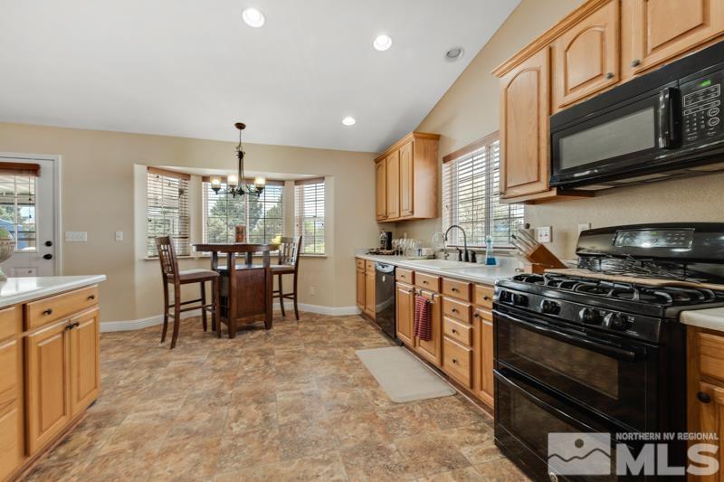 13755 Rancheros Drive Reno, NV 89521 - Photo 4 of 24 a kitchen with stainless steel appliances granite countertop a stove top oven a sink dishwasher a dining table and chairs with wooden cabinets