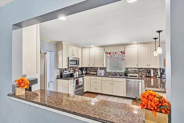 a kitchen with counter top space cabinets stainless steel appliances a sink and a large window