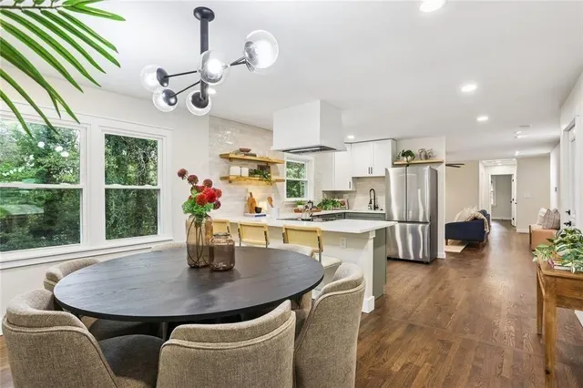 a kitchen with stainless steel appliances a dining table chairs and couches with wooden floor