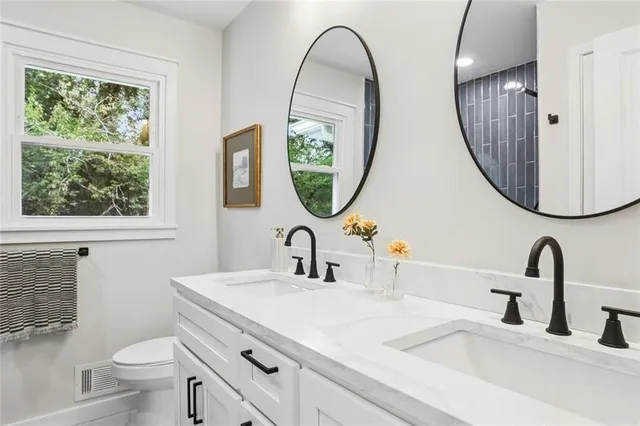 a bathroom with a toilet a sink a mirror and a window