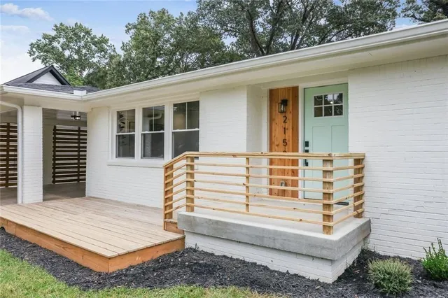 a view of a white house with a large window and flower plants