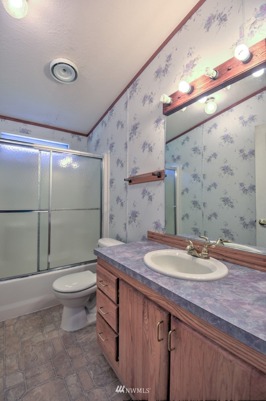 17327 Sargent Road Southwest Rochester, WA 98579 - Photo 15 of 23 a bathroom with a granite countertop sink a toilet a mirror and shower